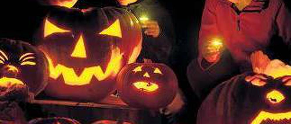 Kinder mit leuchtenden Kürbissen beim Halloween-Fest.