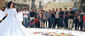 Bunte Wünsche. Raeda Saadeh, Palästinenserin, zeigt ihre Performance "The Wishes Tree am Eingang der Medina von Tunis. Begeistert schrieben die Tunesier ihre geheimsten Wünsche auf Stofffetzen und warfen sie auf das Kleid.