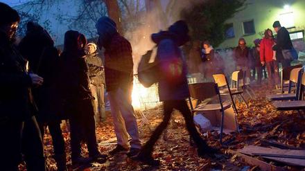 Lagerfeuer statt Räumung. Nach der Besetzung der Kreuzberger Gerhart-Hauptmann- Schule am Sonnabend durch die Flüchtlinge und Kiezinitiativen verzichtete der Bezirk auf einen Polizeieinsatz. Stattdessen kam Bürgermeister Franz Schulz (unten links) zum Schulgelände und verhandelte im Schneetreiben mit den Aktivisten.