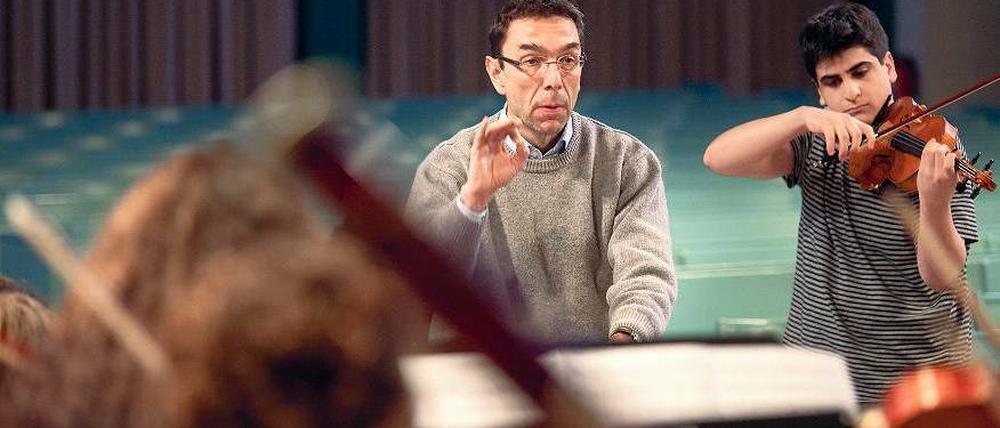 Musikalischer Einsatz. Lehrer Martin Burggaller dirigiert, sein Schüler Varoujan Simonian spielt die Geige beim Weihnachtskonzert des Arndt-Gymnasiums. Für sein langjähriges Engagement für die musikalische Bildung bekommt Burggaller am Freitag das Bundesverdienstkreuz.Foto: Christian Mang