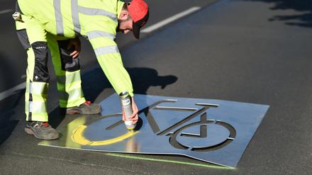 Bauarbeiter sprüht ein Fahrradsymbol auf die Frankfurter Allee. Der Ausbau der Radwege in der Stadt stagniert.