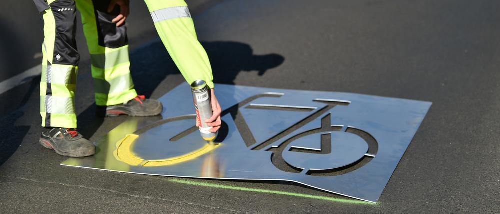 Bauarbeiter sprüht ein Fahrradsymbol auf die Frankfurter Allee. Der Ausbau der Radwege in der Stadt stagniert.
