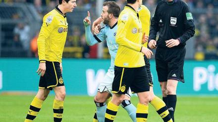 Du gehst gleich. Rafael van der Vaart (in Blau) empört sich über das harte Einsteigen von Robert Lewandowski (links). Der Dortmunder Stürmer sieht die Rote Karte, der Hamburger erhält für seine handgreifliche Beschwerdeführung Gelb. Foto: AFP