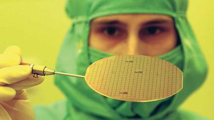 Mit Mundschutz und Fingerfertigkeit. Die Computerchips sind manchmal tausendmal kleiner als ein Haar. Schon ein kleines Staubkorn oder ein Fussel am Arbeitsplatz kann ihre Arbeit zerstören. Deshalb tragen die Techniker besondere Schutzkleidung. Foto:dpa/tmn
