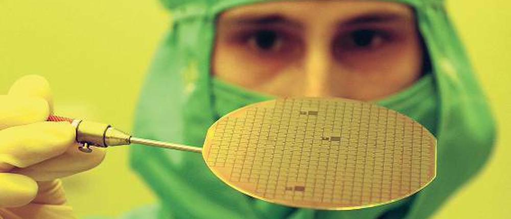 Mit Mundschutz und Fingerfertigkeit. Die Computerchips sind manchmal tausendmal kleiner als ein Haar. Schon ein kleines Staubkorn oder ein Fussel am Arbeitsplatz kann ihre Arbeit zerstören. Deshalb tragen die Techniker besondere Schutzkleidung. Foto:dpa/tmn