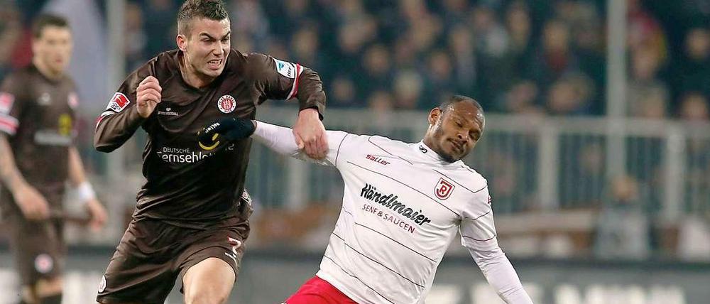 Kraftakt: St. Paulis Dennis Daube (l.) setzt sich gegen Regenburgs Julian De Guzman durch.