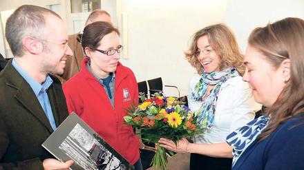 Ein kleines Dankeschön. Vertreter der Charitas haben Blumen und ein Foto das Schlafplatzes eines Obdachlosen dabei. Die beiden Hauptorganisatorinnen der Tagesspiegel-Weihnachtsspendenaktion, Annette Kögel und Stefanie Dujardin-Sommer (r.) vom Spendenverein, freuen sich. Auch Judith Scapolo (nicht im Bild) organisiert immer kräftig mit. 
