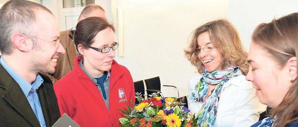 Ein kleines Dankeschön. Vertreter der Charitas haben Blumen und ein Foto das Schlafplatzes eines Obdachlosen dabei. Die beiden Hauptorganisatorinnen der Tagesspiegel-Weihnachtsspendenaktion, Annette Kögel und Stefanie Dujardin-Sommer (r.) vom Spendenverein, freuen sich. Auch Judith Scapolo (nicht im Bild) organisiert immer kräftig mit.
