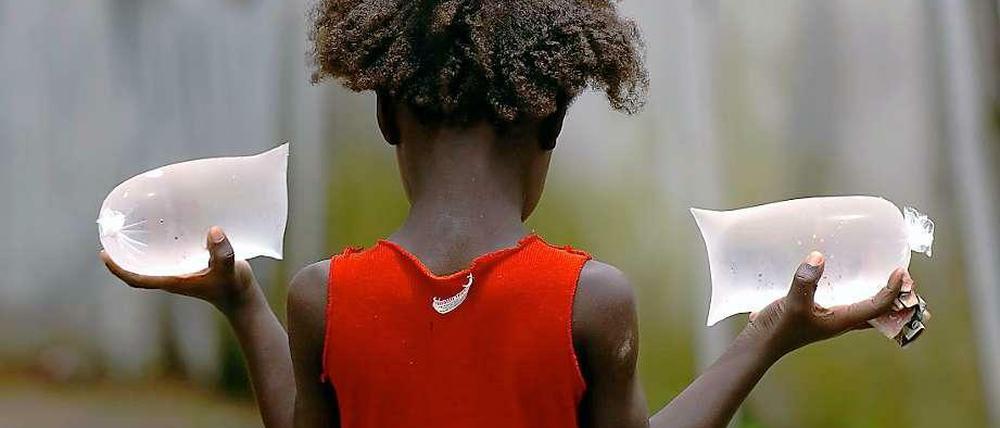 Ein Mädchen in Monrovia mit den beliebten Wasserpacks, die auf der Straße verkauft werden.