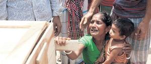 Hinterbliebene. Eine Frau weint um ihre getötete Schwester. Auf dem Schoß hat sie die Tochter der Toten. Viele der Arbeiterinnen in der eingestürzten Fabrik in Bangladesch waren alleinerziehende Mütter. Was aus den Waisen wird, ist unklar. Foto: Abir Abdullah/dpa