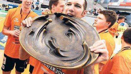 Hungrig auf die Schale. Scott Touzinsky von den BR Volleys prüft die Bissfestigkeit der seltsamen Volleyball-Trophäe. Foto: dpa