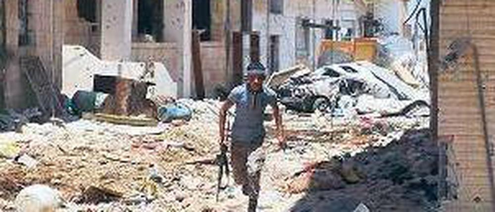 Deckung suchen. Ein Rebell in der zum Teil zerstörten Stadt Daraa. Foto: AFP