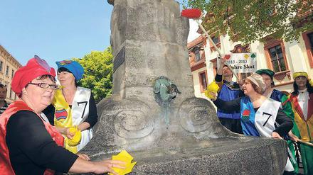Ohne Kontra und Re reinigen die Teilnehmer des „lebenden Skatspiels“ den Skatbrunnen in Altenburg. Die Stadt feiert „200 Jahre Skat“.