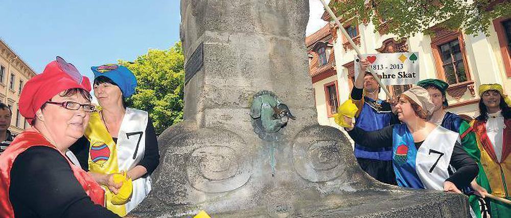 Ohne Kontra und Re reinigen die Teilnehmer des „lebenden Skatspiels“ den Skatbrunnen in Altenburg. Die Stadt feiert „200 Jahre Skat“.