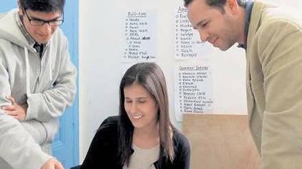 Tunisia-Live-Chef Youssef Gaigi (r.) bespricht journalistische Texte mit seinem Team. Im Büro hängt ein Protestplakat von Demonstranten.