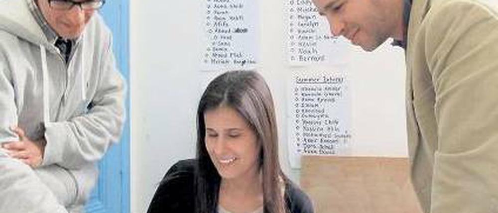 Tunisia-Live-Chef Youssef Gaigi (r.) bespricht journalistische Texte mit seinem Team. Im Büro hängt ein Protestplakat von Demonstranten.