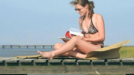 Lohnende Kombination: Wer sich in den Ferien in Eigenregie weiterbilden will, kann auch einfach ein bisschen Fachlektüre mit an den Strand nehmen. Aber Vorsicht: Ob auch die CD-Rom mit dem Buchhaltungskurs mit ins Gepäck darf, sollte man sich gut überlegen. Foto: dpa