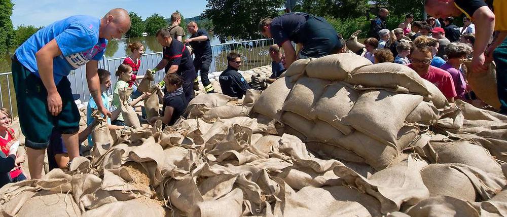 Freiwillige Helfer schichten Sandsäcke aufeinander - Zivilcourage in Sachsen