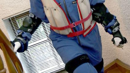 Eine junge Frau versucht im Alterssimulationsanzug eine Treppe hinauf zu steigen
