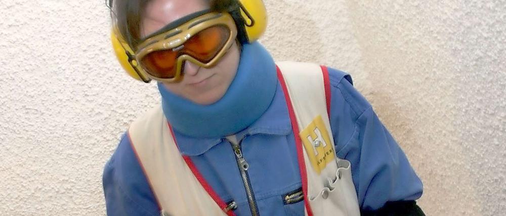 Eine junge Frau versucht im Alterssimulationsanzug eine Treppe hinauf zu steigen