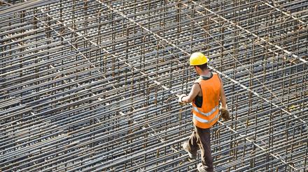 Ein Bauarbeiter schreitet über ein Geflecht aus Stahlstreben, das noch mit Beton ausgegossen werden muss. 