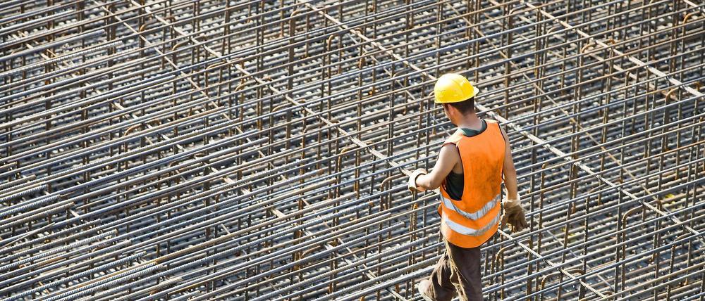 Ein Bauarbeiter schreitet über ein Geflecht aus Stahlstreben, das noch mit Beton ausgegossen werden muss. 