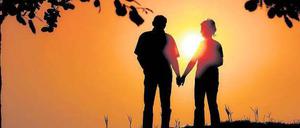Ein Mann und eine Frau stehen Hand in Hand vor einem Sonnenuntergang.