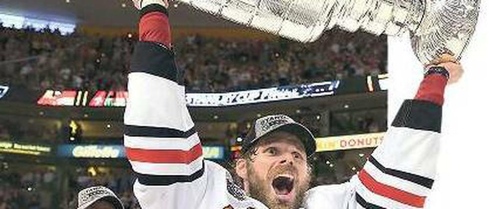 Potthässlich, aber sehr begeht. Chicagos Michal Handzus stemmt den schweren Stanley Cup in die Höhe, nachdem er ihn von Kapitän Jonathan Toews (l.) bekommen hat. Foto: AFP