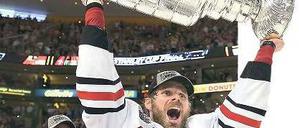 Potthässlich, aber sehr begeht. Chicagos Michal Handzus stemmt den schweren Stanley Cup in die Höhe, nachdem er ihn von Kapitän Jonathan Toews (l.) bekommen hat. Foto: AFP