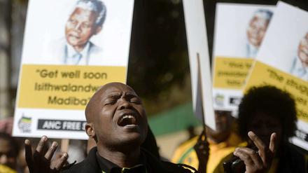 Ein Mann singt vor Plakaten mit dem Text "Get well soon Madiba"
