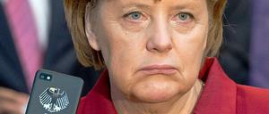Angela Merkel zeigt auf der Cebit die Rückseite eines Smartphones, auf dem ein Bundesadler zu sehen ist.