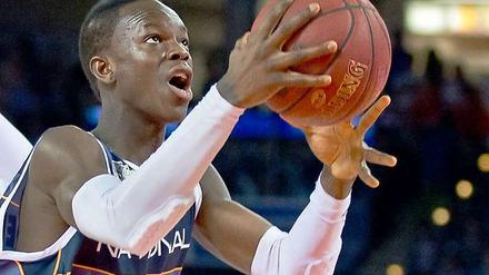 Dennis Schröder hat einen Basketball in der Hand und schaut zum korb.