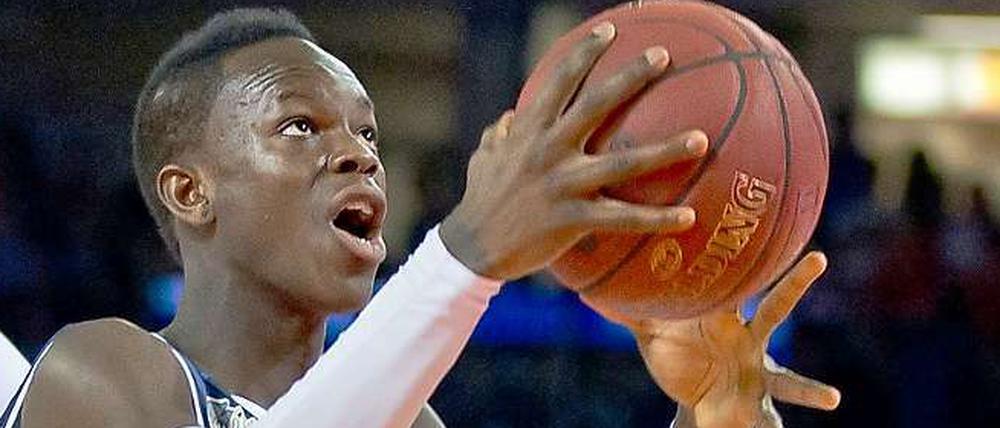 Dennis Schröder hat einen Basketball in der Hand und schaut zum korb.