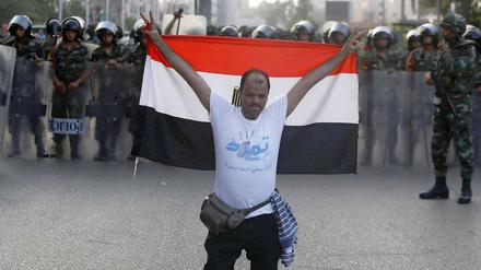 Ein Mitglied der "Tamarod-Rebellen" kniet am Mittwoch in Kairo mit der ägyptischen Flagge vor Armeesoldaten. Zehntausende Ägypter fordern Präsident Mursi seit Tagen auf, zurückzutreten. Am Mittwochabend wurde Mursi von der Armee entmachtet.