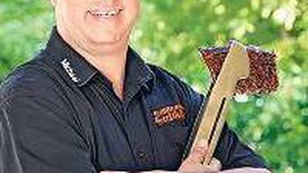 Michael Hoffmann, Deutscher Grillmeister 2013, hält eine Grillzange mit Steak in der Hand. 