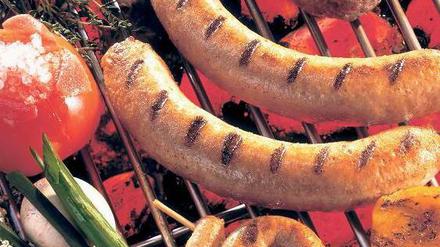 Neben Würsten und einem Steak liegen auf dem Grillrost auch Tomaten, Paprika, und Rosmarin. 