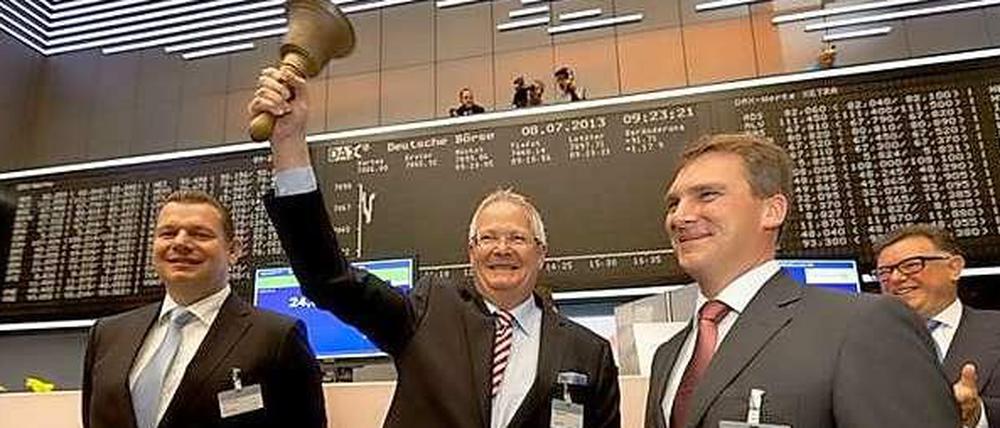 Osram Vorstandsvorsitzender Wolfgang Dehen und sein Finanzchef Klaus Patzak stehen mit zwei weiteren Männern auf dem Frankfurter Börsenparkett vor der Anzeigetafel. Dehen hält die Glocke hoch.