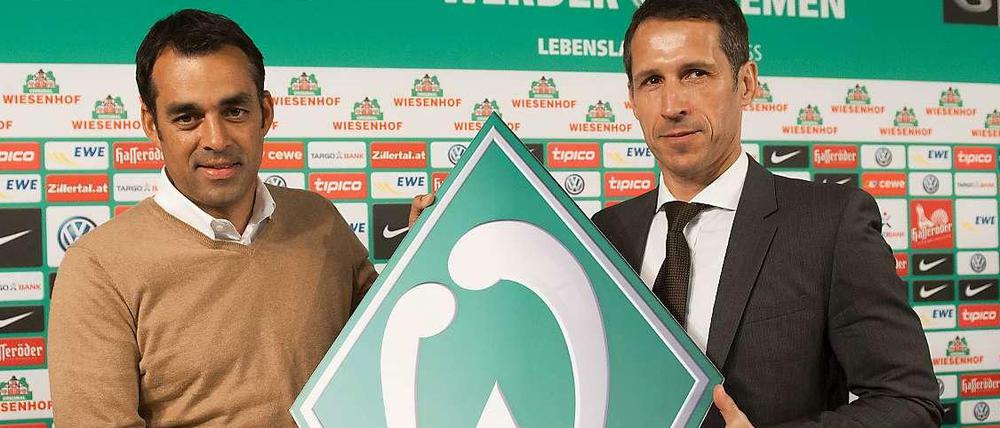  Robin Dutt (l.) und  Thomas Eichin halten das Logo von Werder Bremen.
