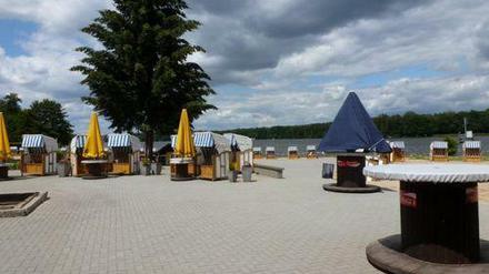 Sonnenschirme und Strandkörbe unter wolkigem Himmel am Strandbad Grünau.