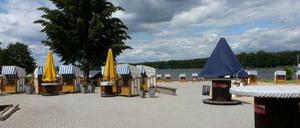 Sonnenschirme und Strandkörbe unter wolkigem Himmel am Strandbad Grünau.