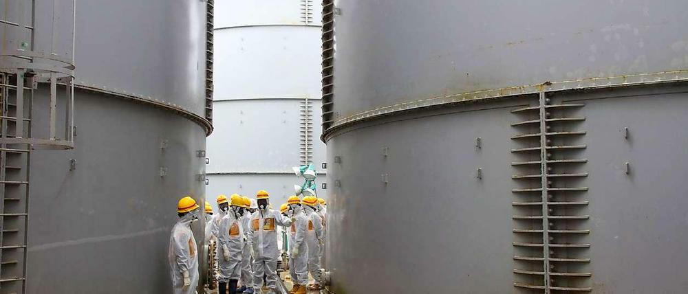 Männer in SChutzkleidung zwischen Wassertanks
