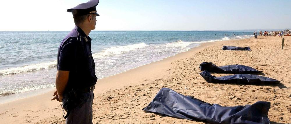 Ein italienischer Polizist steht neben den angeschwemmten Leichen. Der beliebte Badestrand nahe der Stadt Catania wurde gesperrt. 
