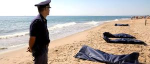 Ein italienischer Polizist steht neben den angeschwemmten Leichen. Der beliebte Badestrand nahe der Stadt Catania wurde gesperrt. 