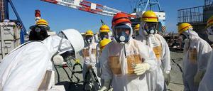 Vor wenigen Tagen hat Industrieminister Tshimitsu Motegi (roter Helm) die havarierten Atomanlagen in Fukushima besucht. Er ließ sich von Mitarbeitern der Betreiberfirma Tepco erklären, warum seit Monaten radioaktiv verseuchtes Wasser in den Pazifik gelangt. Tepco hat das Foto selbst herausgegeben. 