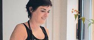 Die Inhaberin vor ihrem Schaufenster, in dem viele rundliche Vasen in Pastellfarben stehen.