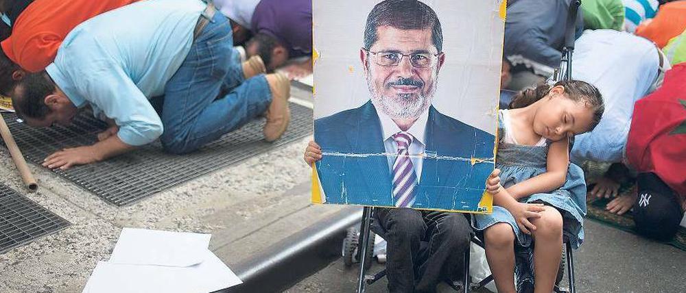 Gebet als Protest. Mehrere hundert Menschen demonstrieren in New York gegen das gewaltsame Vorgehen der Übergangsregierung in Kairo gegen die Muslimbruderschaft. Ein Kind hält dabei ein Plakat mit dem Konterfei des gestürzten Präsidenten Mohammed Mursi hoch.