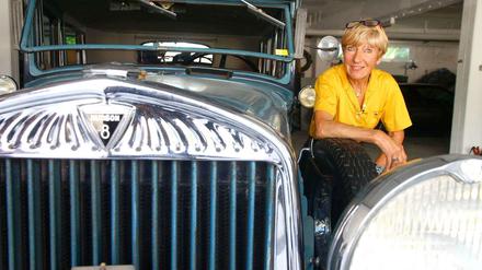 Heidi Hetzer hockt im gelben Shirt neben der Motorhaube ihre Hudson-Oldtimers.