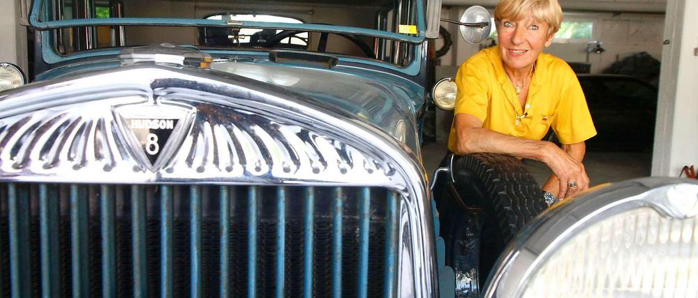 Heidi Hetzer hockt im gelben Shirt neben der Motorhaube ihre Hudson-Oldtimers.