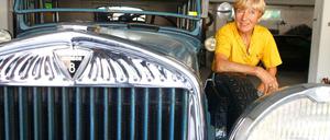 Heidi Hetzer hockt im gelben Shirt neben der Motorhaube ihre Hudson-Oldtimers.