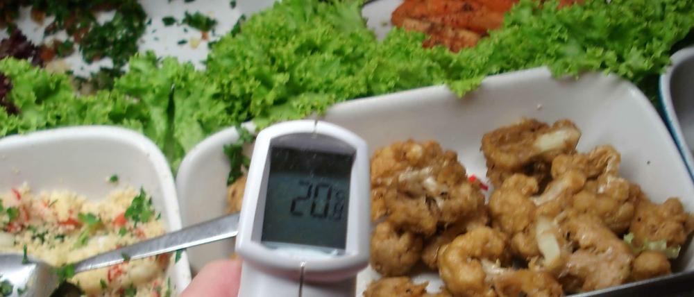 Lebensmittelkontrolle in Berlin - die Temperatur von gebratenem Geflügel in einer Essensausgabe wird geprüft.